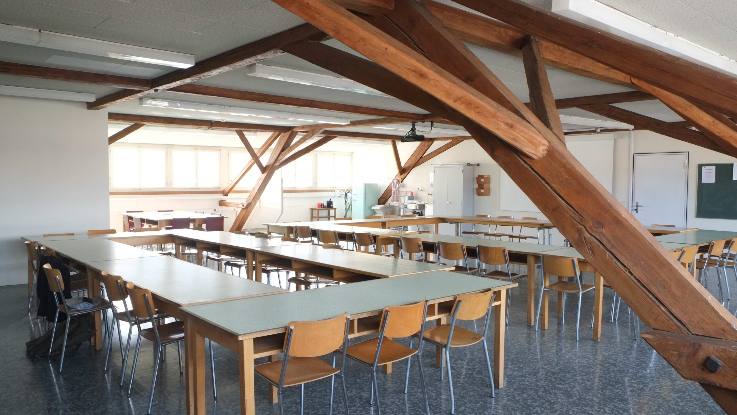 MarieOtto Raum – Tischreihen und Holzbalken